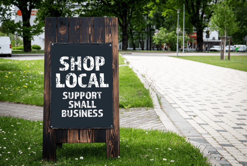 Business Clarity small sign in grass saying shop local , support small businesses on chalkboard